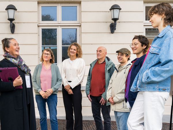 Eine Gruppe hört einer Stadtführerin zu.