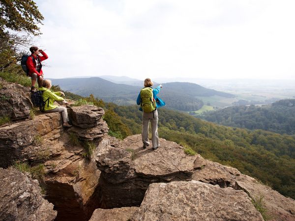 Drei Wanderer schauen von der Kante der Hohenstein-Klippen