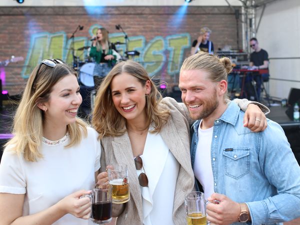 Zwei Frauen und ein Mann stehen vor einer Bühne