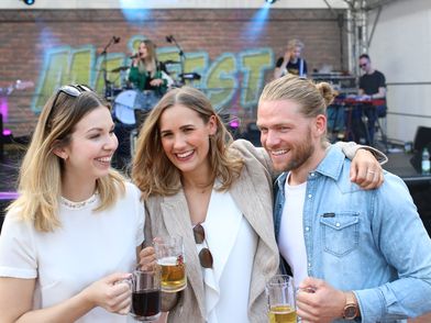 Zwei Frauen und ein Mann stehen vor einer Bühne