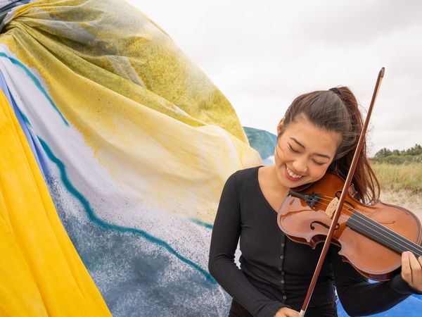 Frau mit Violine am Strand