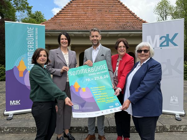 Fünf Menschen halten ein Plakat in die Kamera.