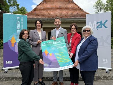 Fünf Menschen halten ein Plakat in die Kamera.