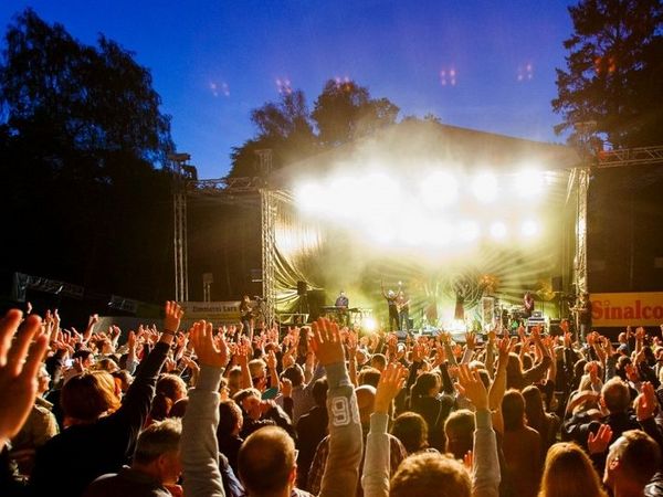 Mitsingende Menschenmenge vor der erleuchteten Bühne bei Dämmerung
