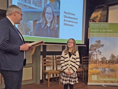 Landrat Marco Prietz überreicht Annalena Schmidtchen eine Urkunde zur Aufnahme in die „Hall of NORDPFADE“