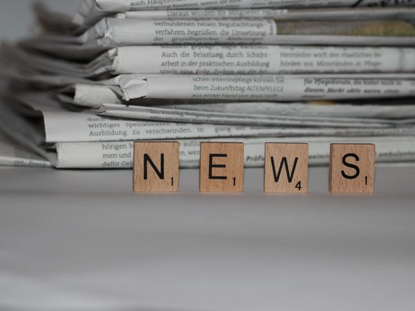 Zeitungsstapel mit Scrabble-Steinen auf denen "News" steht