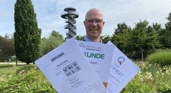 Christian Wandscher mit den drei touristischen Zertifikaten „Besonders kinderfreundlich“, „Barrierefreiheit geprüft“ und „ServiceQualität Deutschland“, © Gartenkulturzentrum Niedersachsen - Park der Gärten gGmbH