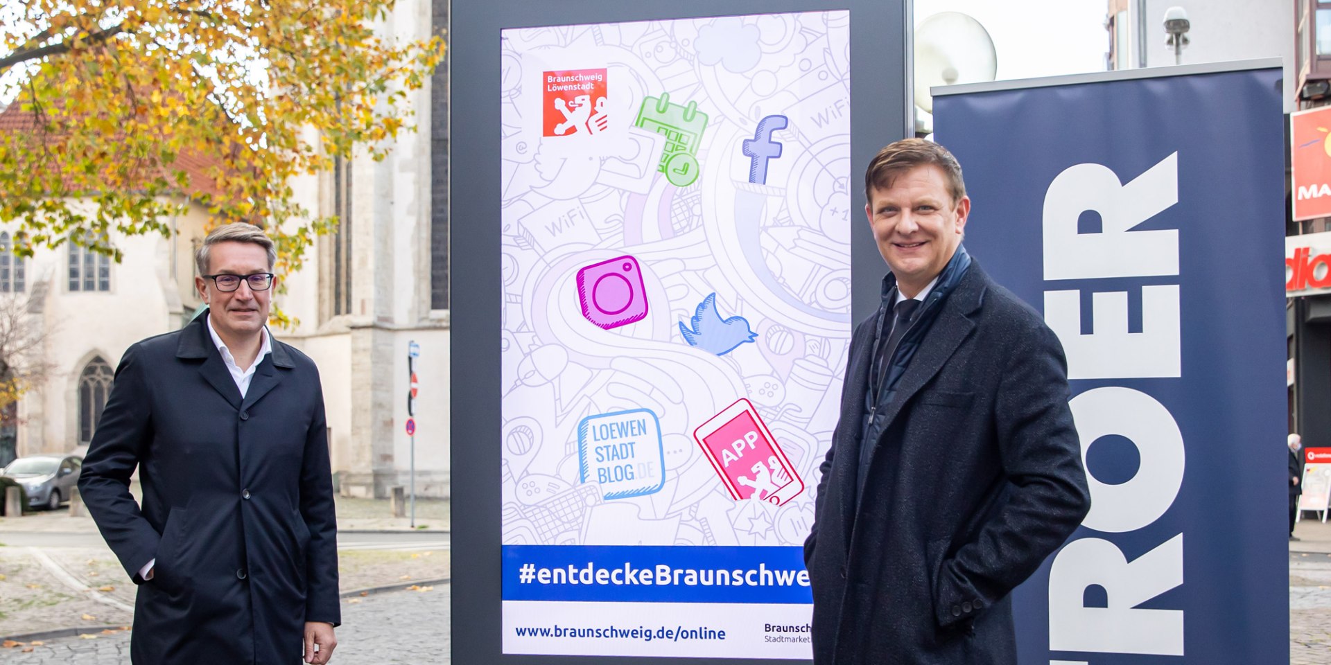 Gerold Leppa, Geschäftsführer des Stadtmarketings, und Harald Rotter, Ströer-Niederlassungsleiter Braunschweig, präsentieren einen der neuen Cityscreens am Standort Ecke Schild/Meinhardshof in Braunschweig., © Braunschweig Stadtmarketing GmbH/Philipp Ziebart