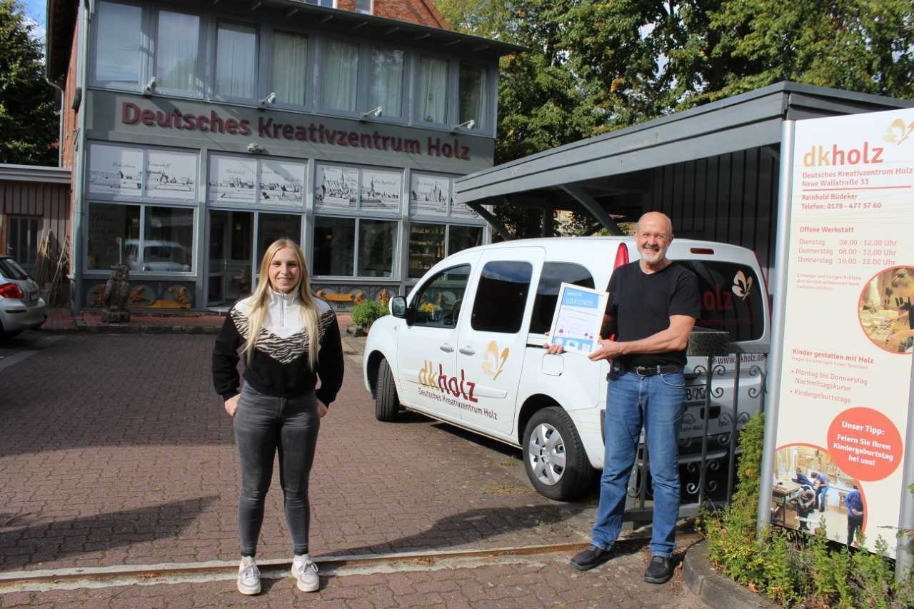 Reinhold Büdeker, Leiter des Deutschen Kreativzentrum Holz in Nienburg freut sich mit Marie Witte von der Mittelweser-Touristik GmbH über die Kinderferienland-Auszeichnung, © Mittelweser-Touristik GmbH